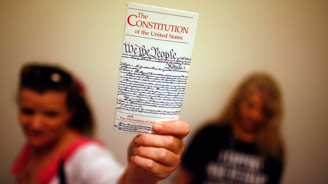 Woman holds up copy of U.S. Constitution.