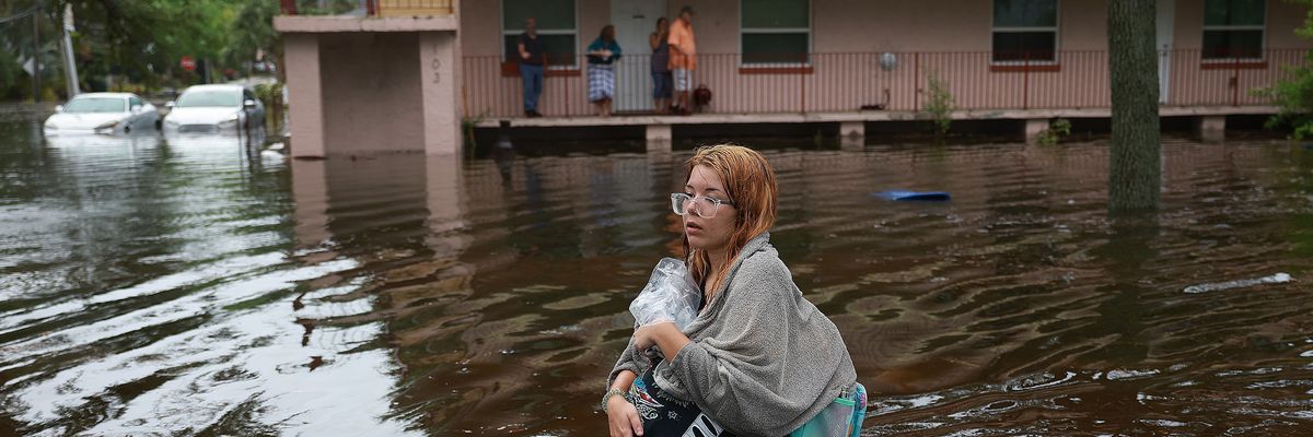 woman wades through flood waters from Hurricane Idalia