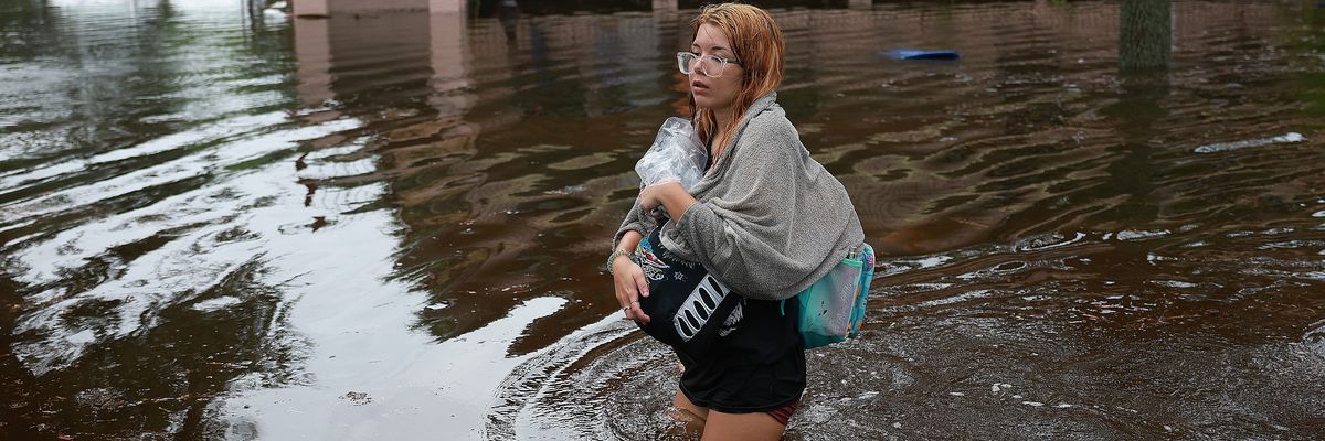 woman wades through flood waters from Hurricane Idalia