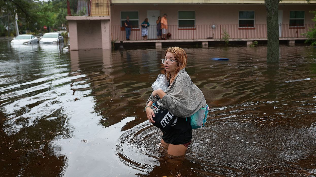woman wades through flood waters from Hurricane Idalia