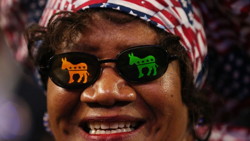 Woman wears sunglasses with Democratic donkeys on the lenses.