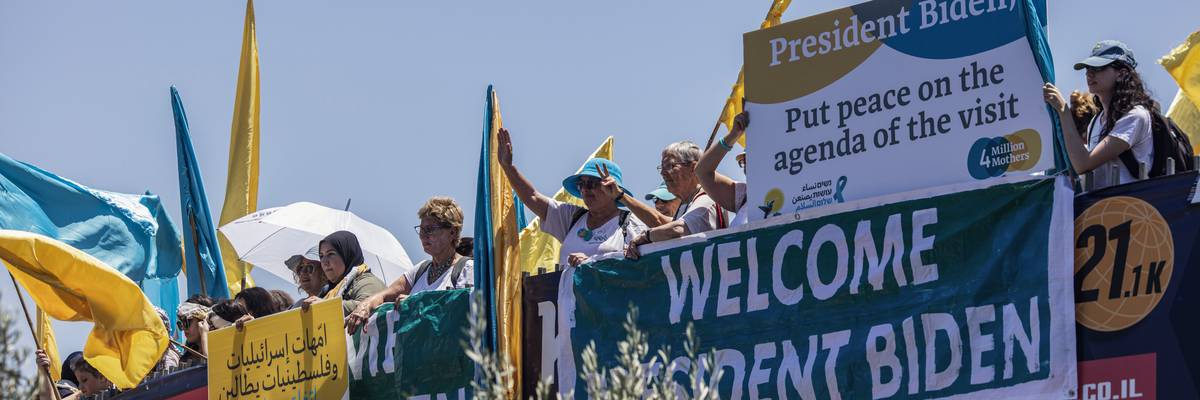 Women dressed in blue and yellow hold up signs.