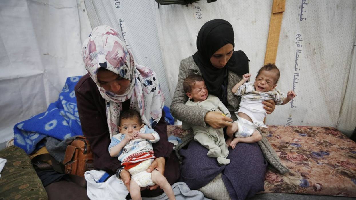 women hold three malnourished Gaza triplets