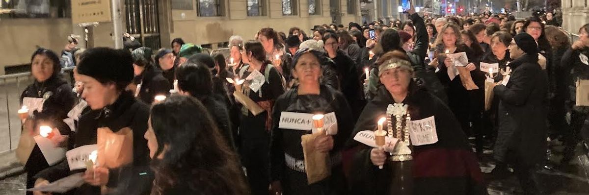 Women march in black carrying candles and signs reading, "Nunca."