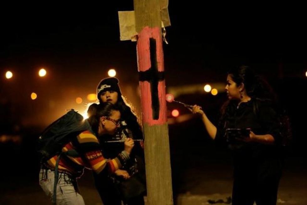 Women paint a black cross on a lamp post to commemorate missing and murdered women in Juarez, Mexico. (Photo: Reuters)