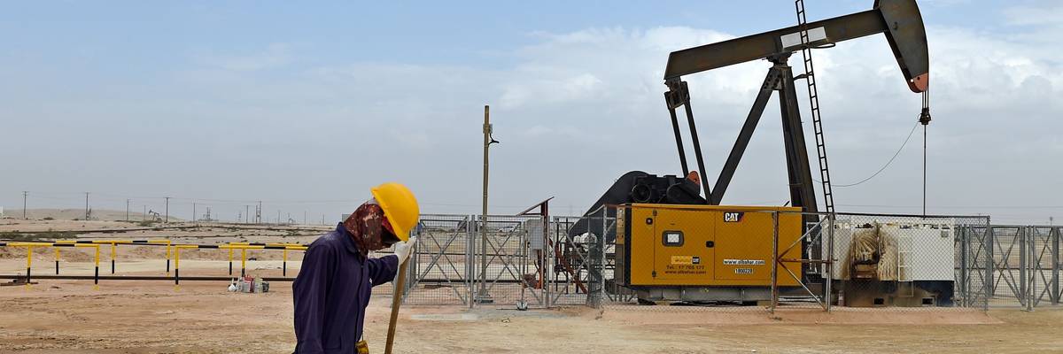 Worker with pump jack in Bahrain oil field.