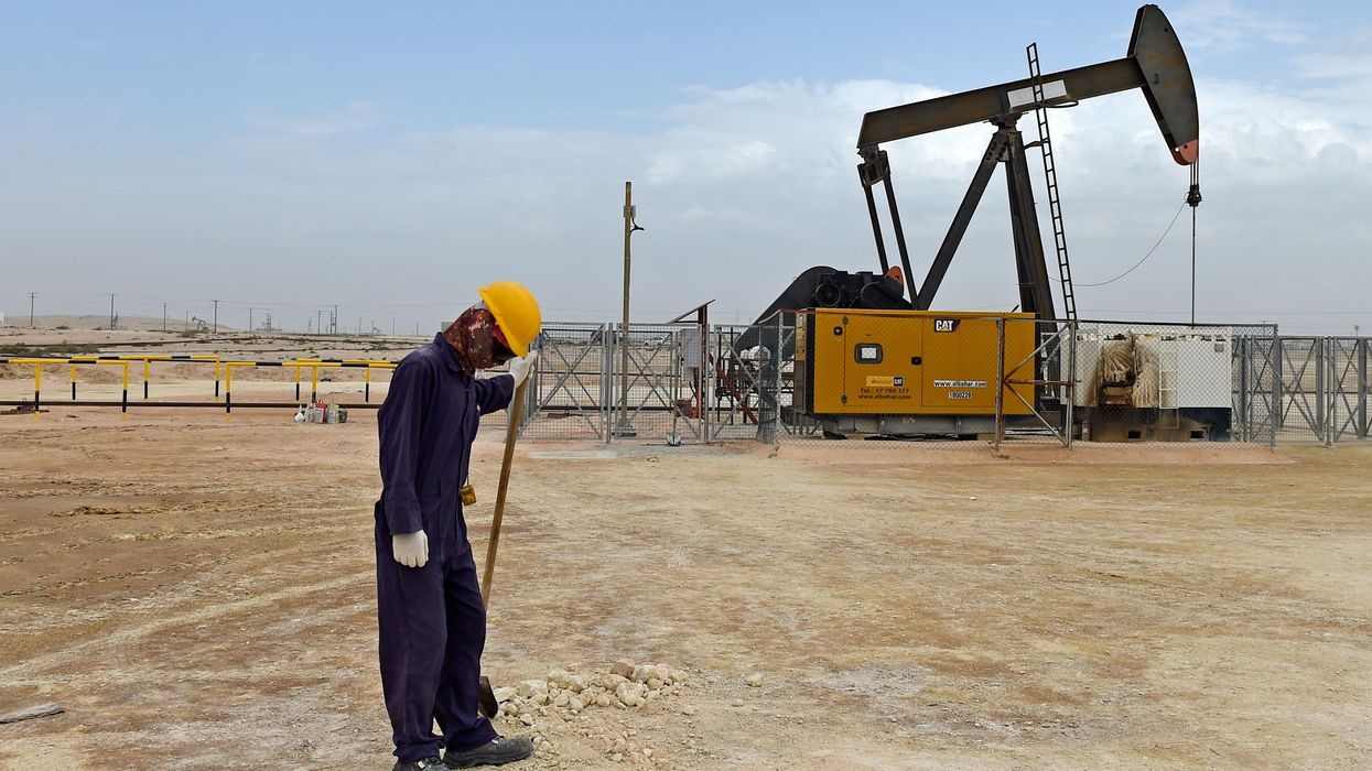 Worker with pump jack in Bahrain oil field.