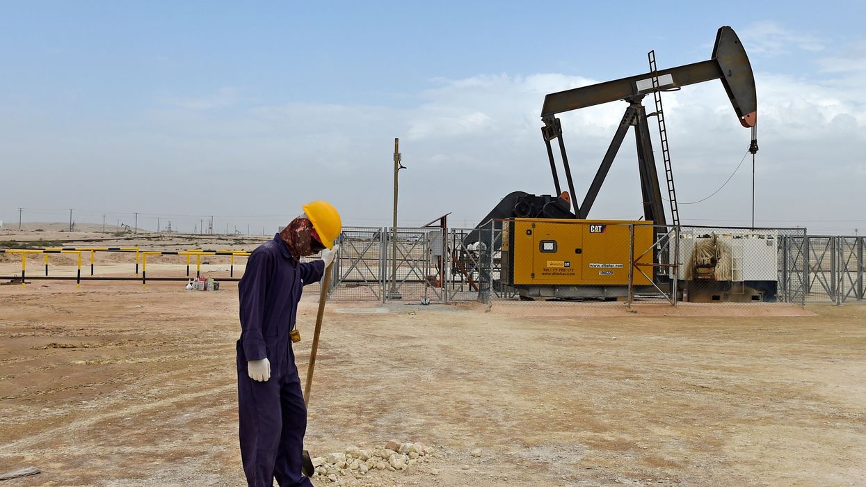 Worker with pump jack in Bahrain oil field.