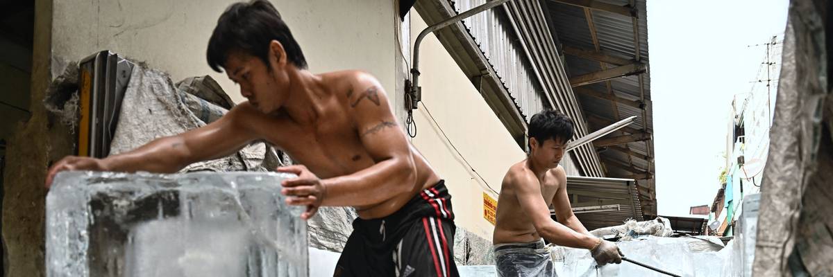 Workers move blocks of ice into a storage unit at a fresh market during heatwave conditions in Bangkok, Thailand on April 25, 2023.