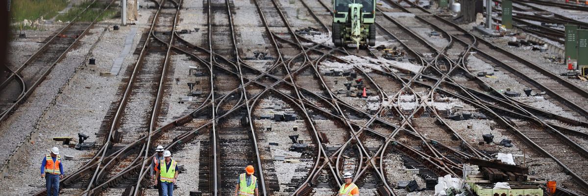 Workers service the tracks at a railroad yard