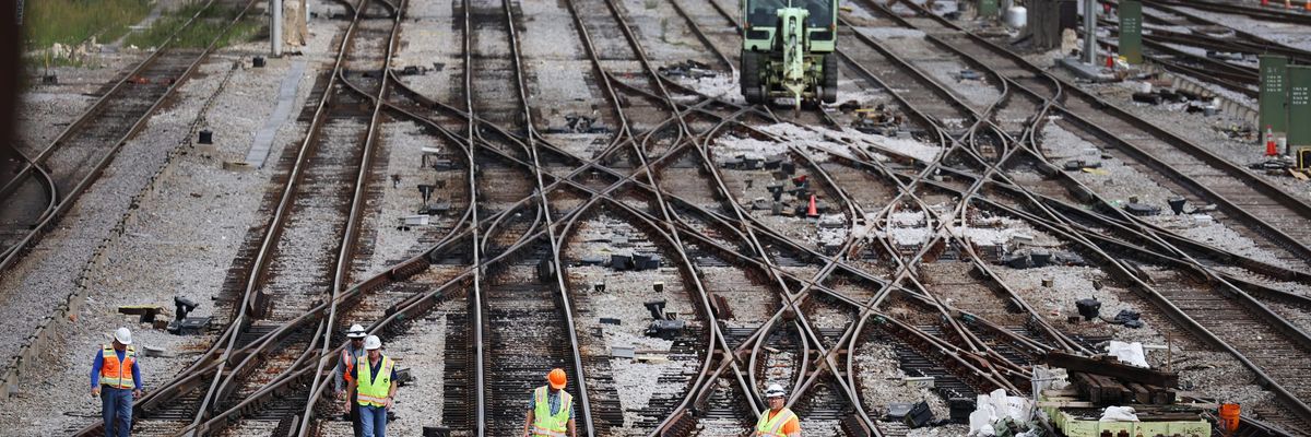 Workers service the tracks at a railroad yard 