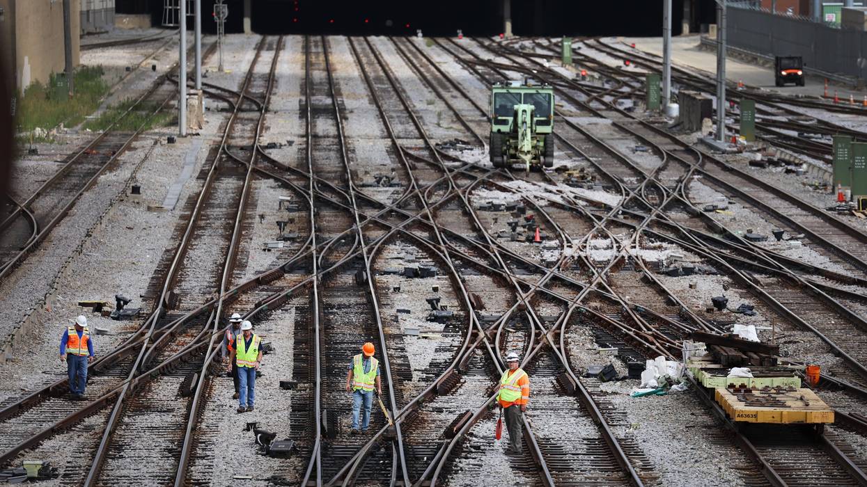 Workers service the tracks at a railroad yard