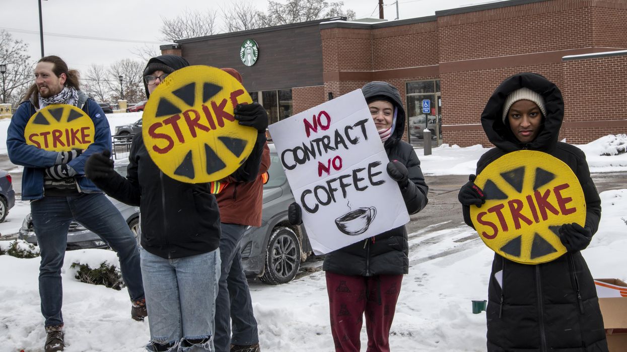 Workers stand in the snow with signs protesting Starbucks.