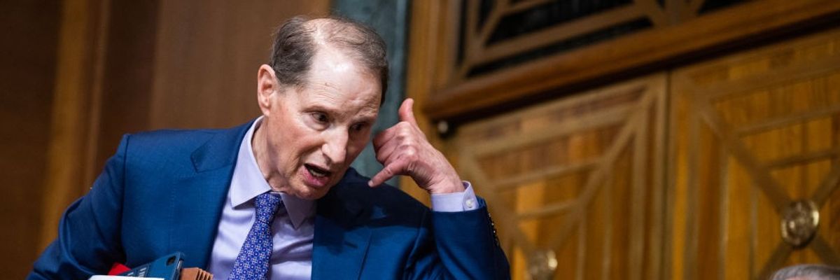 Wyden holds hands up like he's making a phone call