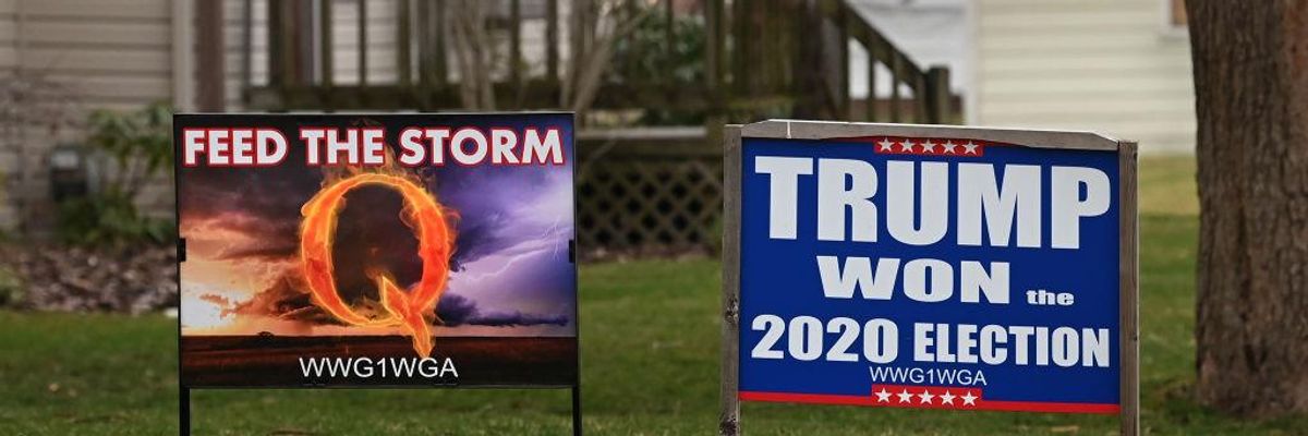 Yard signs including one depicting the QANON conspiracy theory and the other denying Trump's election loss in 2020.