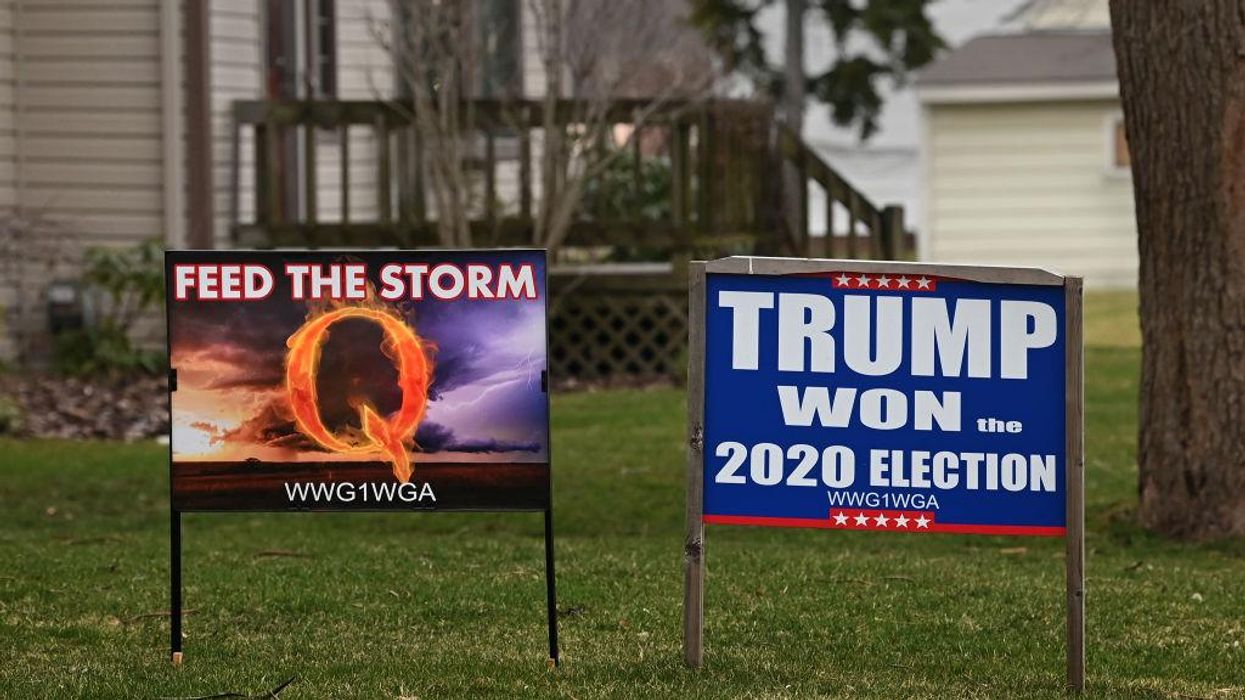 Yard signs including one depicting the QANON conspiracy theory and the other denying Trump's election loss in 2020.