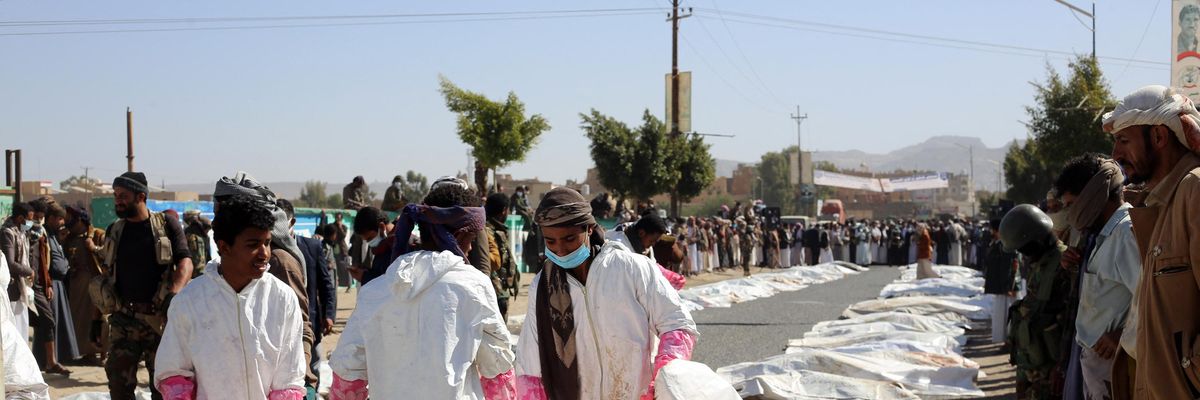 Yemeni medical teams carry body bags containing corpses of those killed in airstrikes on a prison in northern Yemen on January 25, 2022.