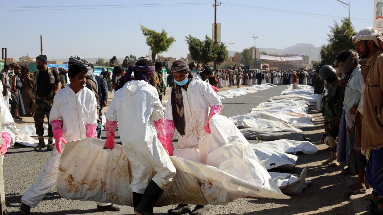 Yemeni medical teams carry body bags containing corpses of those killed in airstrikes on a prison in northern Yemen on January 25, 2022.