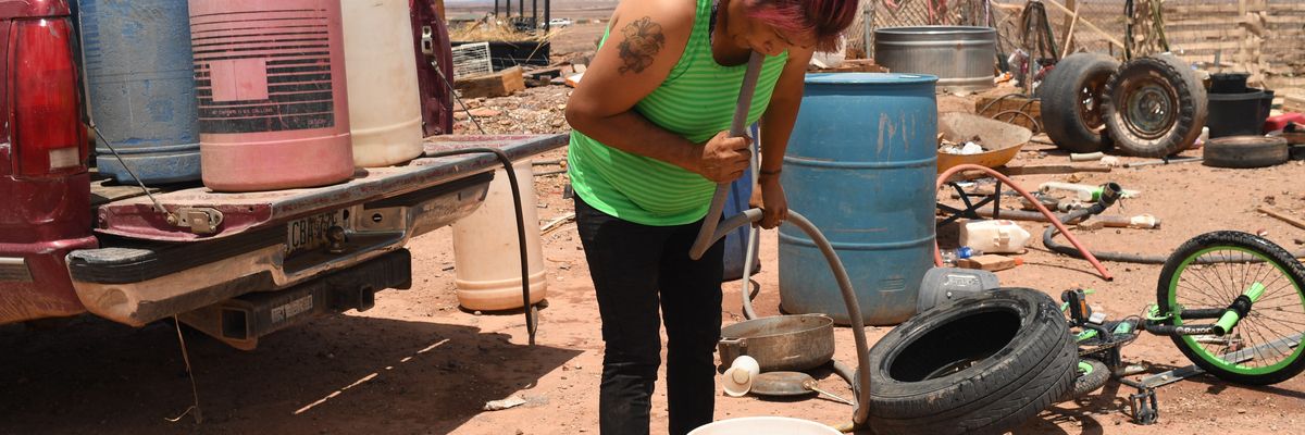 Yolinda Mejia siphons water into a bucket to use for laundry outside her home on the Navajo reservation on July 4, 2022.