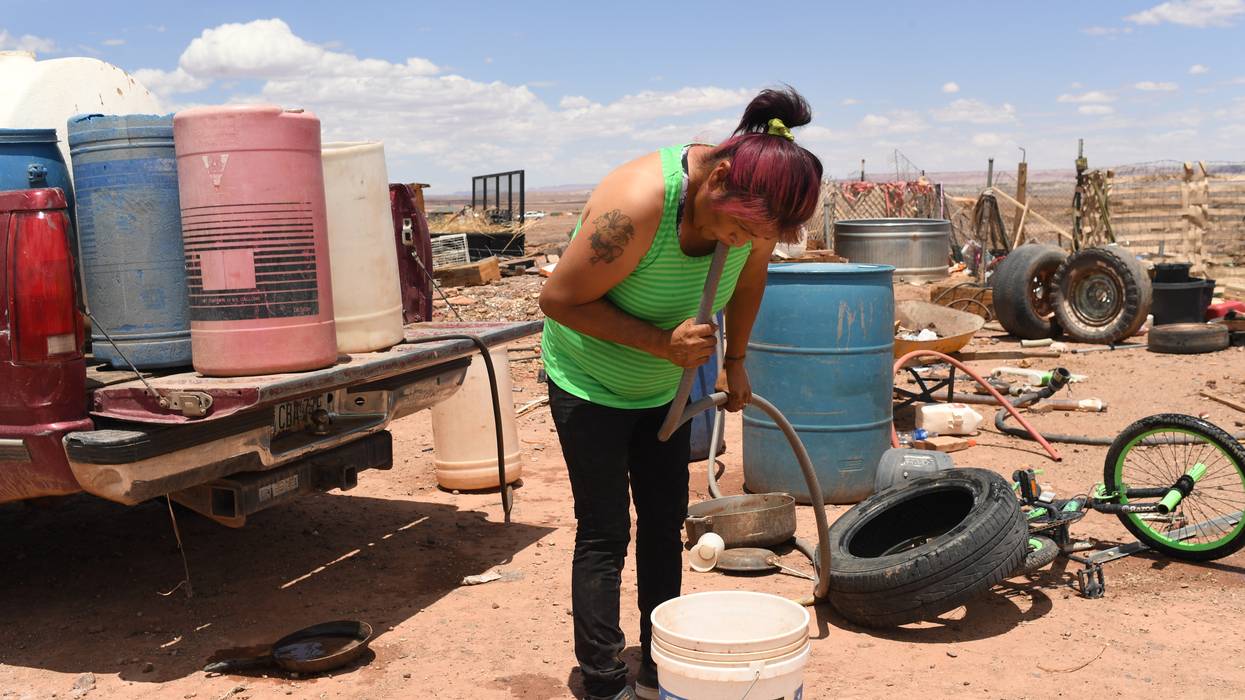 Yolinda Mejia siphons water into a bucket to use for laundry outside her home on the Navajo reservation on July 4, 2022.