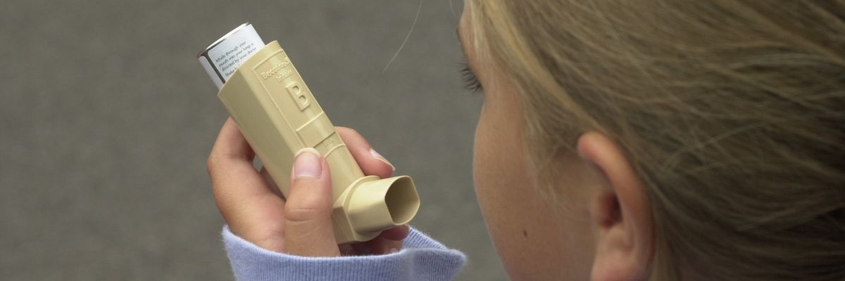 Young girl using asthma inhaler. 