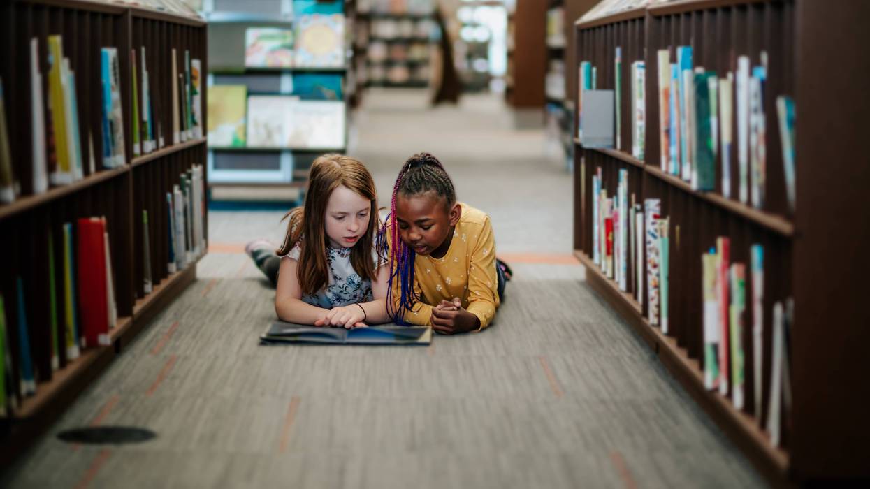 young girls laying on floor reading a picture book