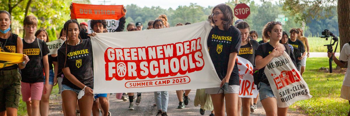 Young organizers hold up a banner celebrating the "Green New Deal for Schools Summer Camp 2023."
