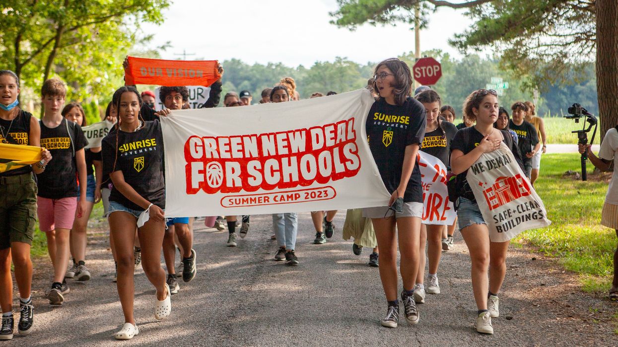 Young organizers hold up a banner celebrating the "Green New Deal for Schools Summer Camp 2023."