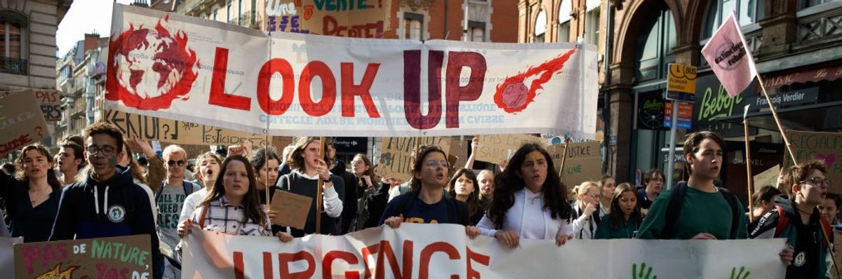 Young people march with white banners.