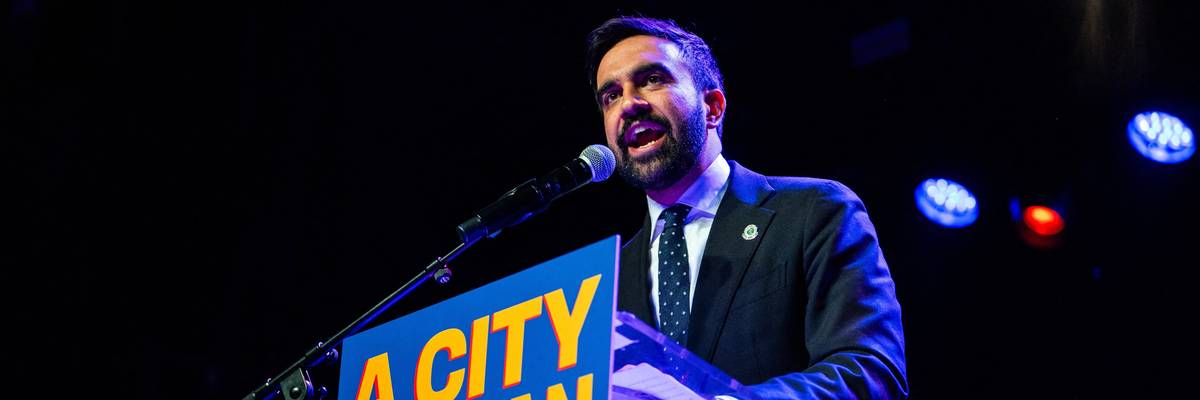 Zohran Mamdani speaks enthusiastically into the microphone at a rally at Brooklyn Steel