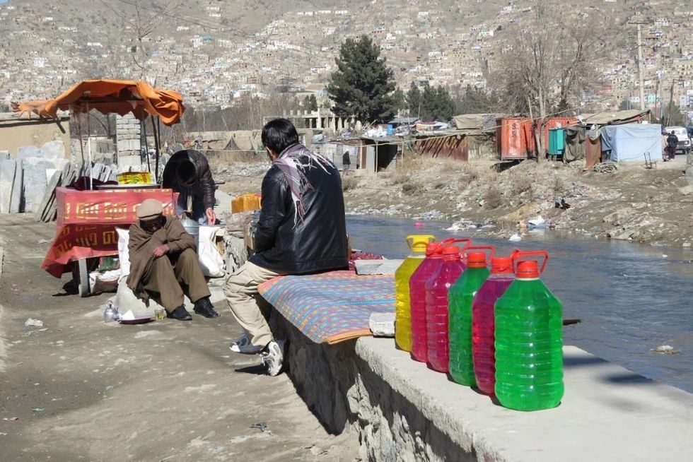 Zuhair's mother was sitting on the ledge in a blue burqa. Houses can be seen on the hill.
