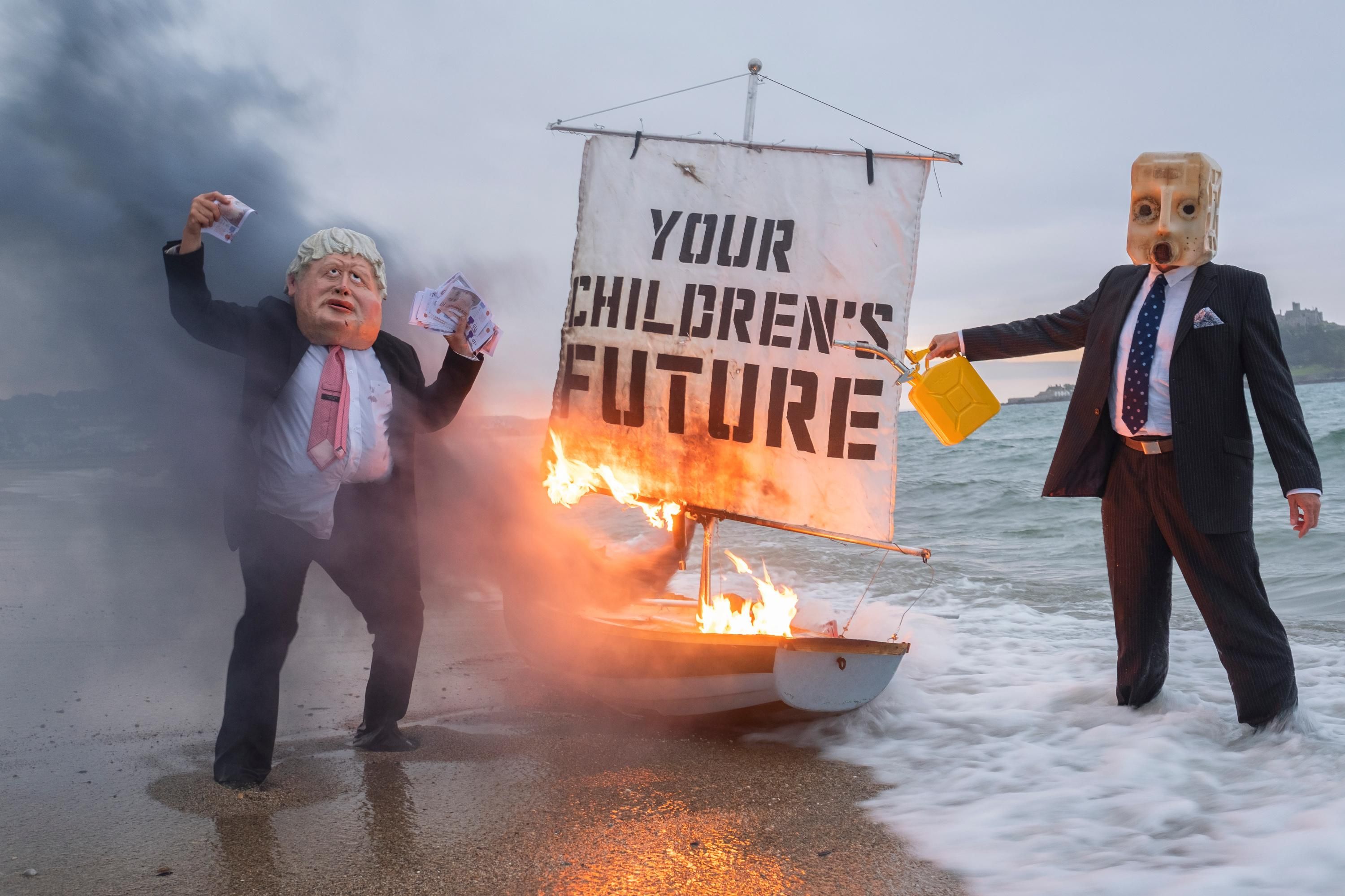 Ocean Rebellion staged a theatrical action with a Boris Johnson head and an "Oil head" burning a boat on Marazion beach on June 5, 2021 in Cornwall, United Kingdom.(Photo: Gav Goulder/In Pictures via Getty Images)