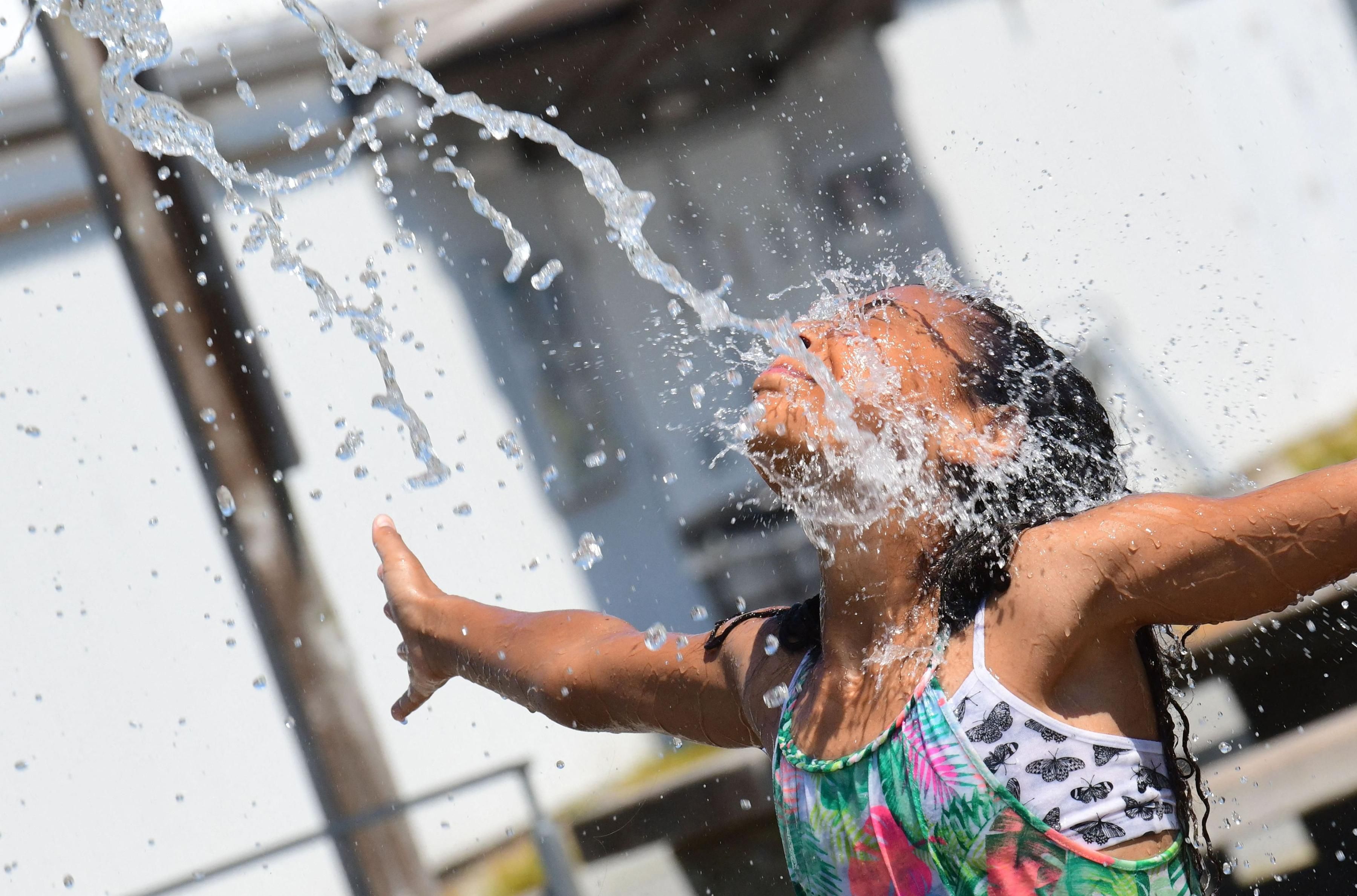 A child cools off at a community water park amid sweltering heat