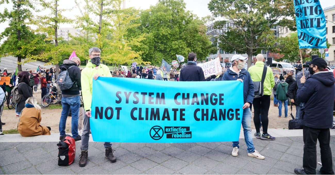 "System change not climate change" is written on a banner at a rally