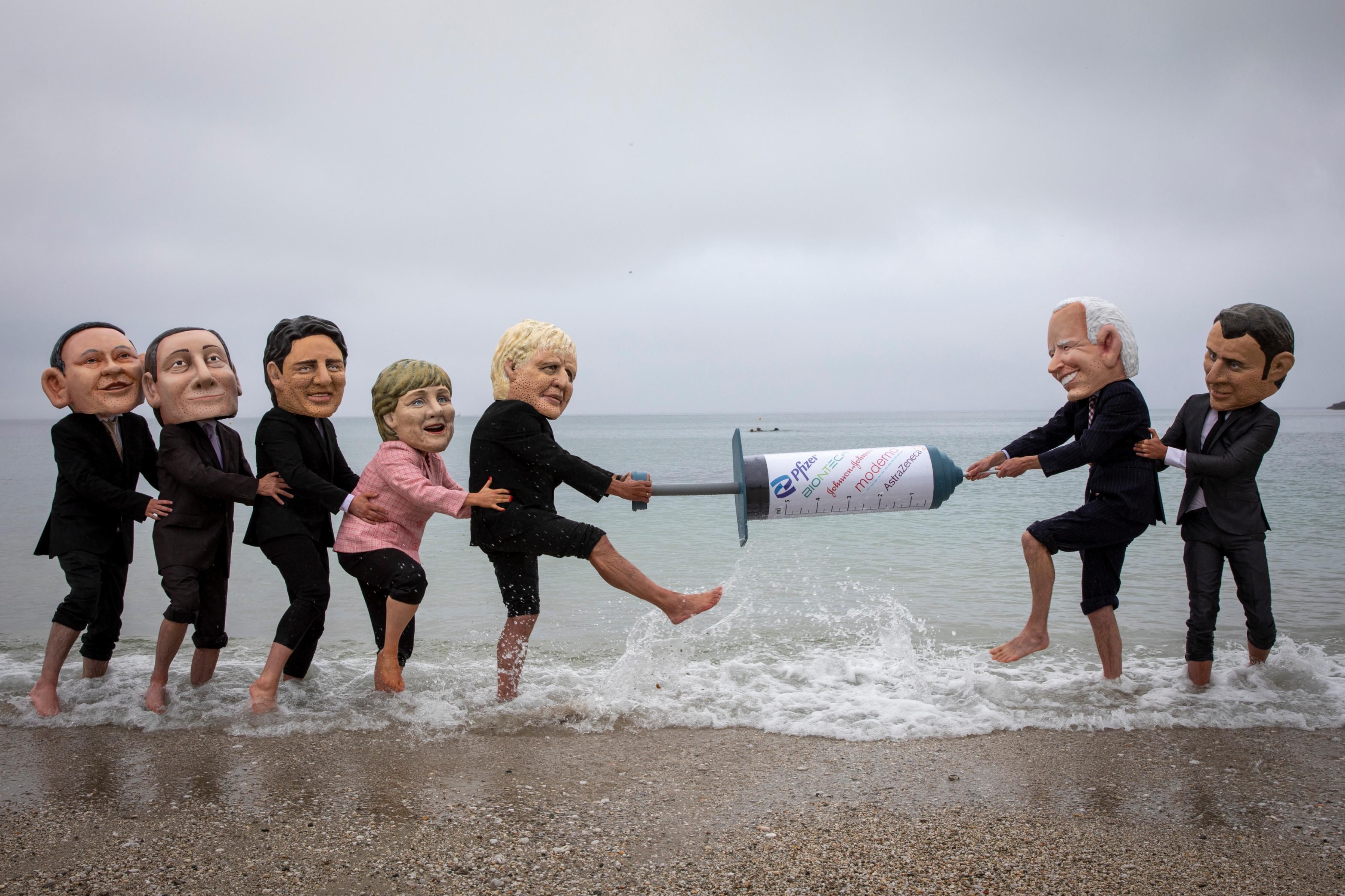 Vaccine equity campaigners posing as G7 leaders tussle over a giant mock syringe