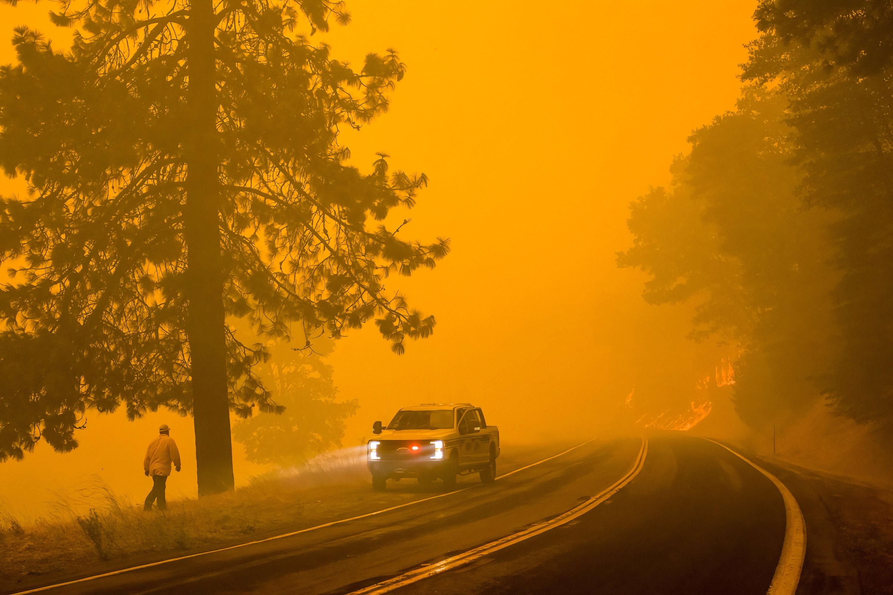 A firefighter turns around as active flames reach highway 70 in California on July 24, 2021. (Photo: Ty O'Neil/SOPA Images/LightRocket via Getty Images)