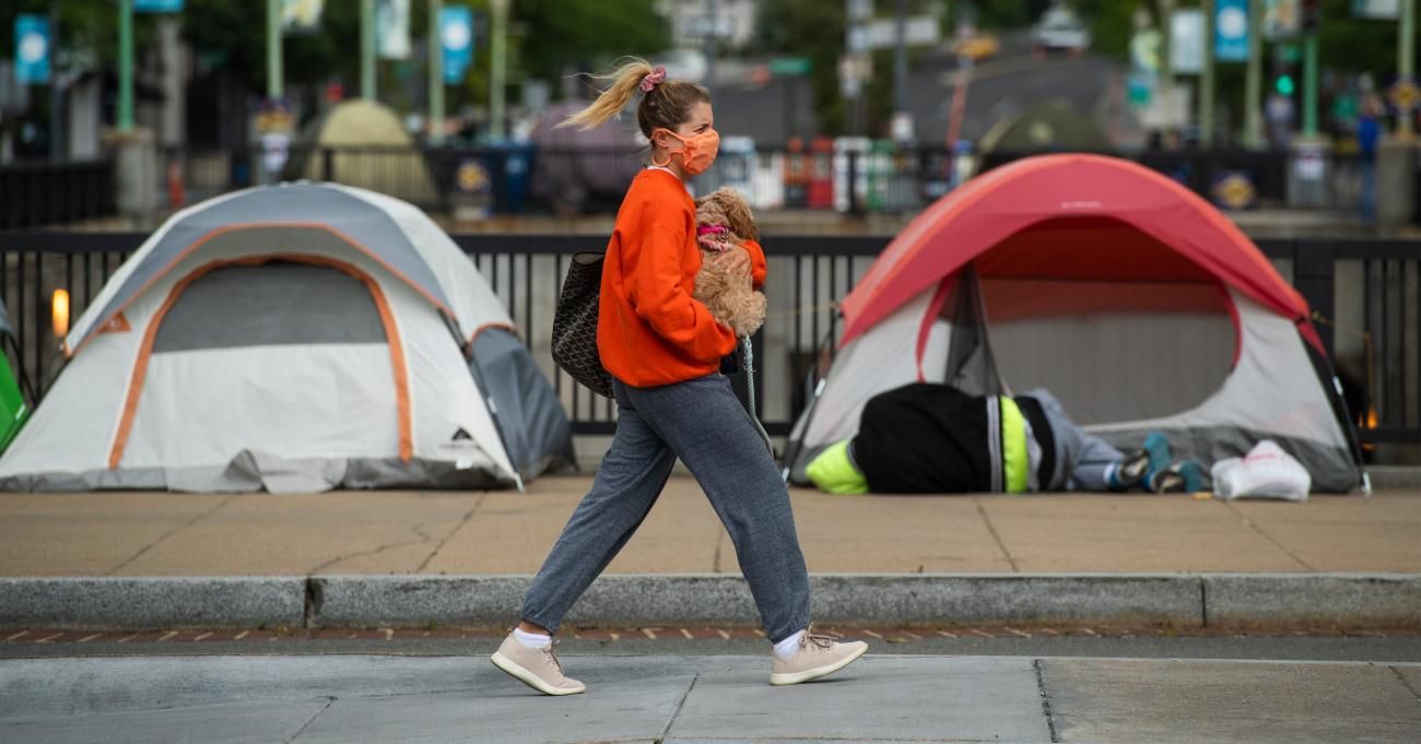 A woman walks past tents used by people experiencing homelessness in Washington, D.C.