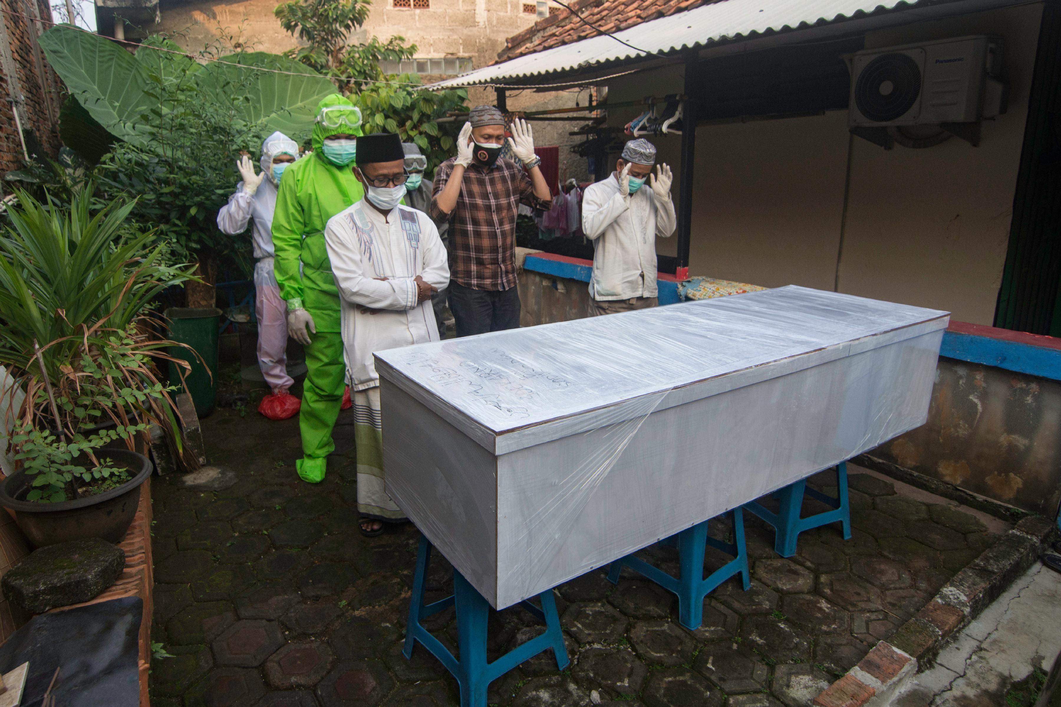 People attend a funeral of a coronavirus victim in Indonesia