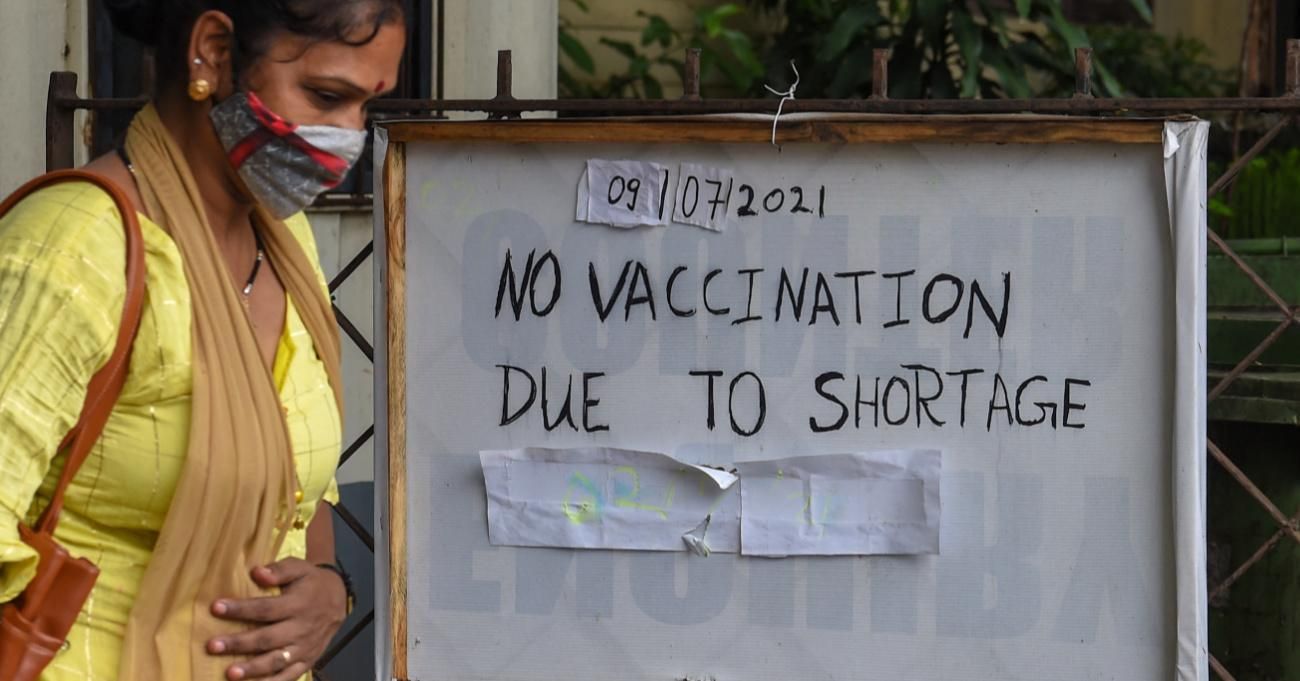 A woman walks past a notice announcing unavailability of Covid-19 vaccine doses.