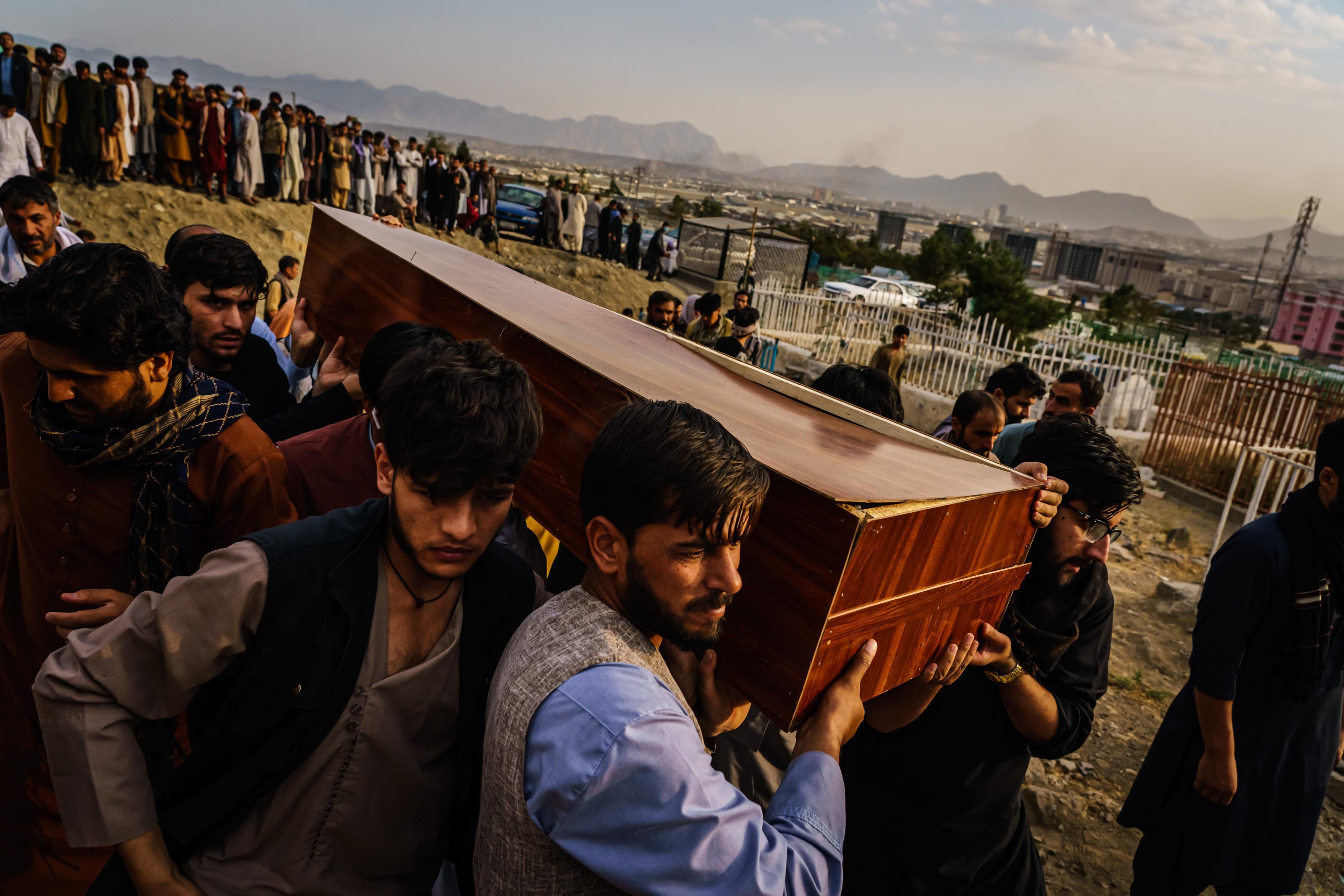 Caskets for the dead are carried towards the gravesite as relatives and friends attend a mass funeral for members of a family that is said to have been killed in a U.S. drone airstrike, in Kabul, Afghanistan, Monday, Aug. 30, 2021.