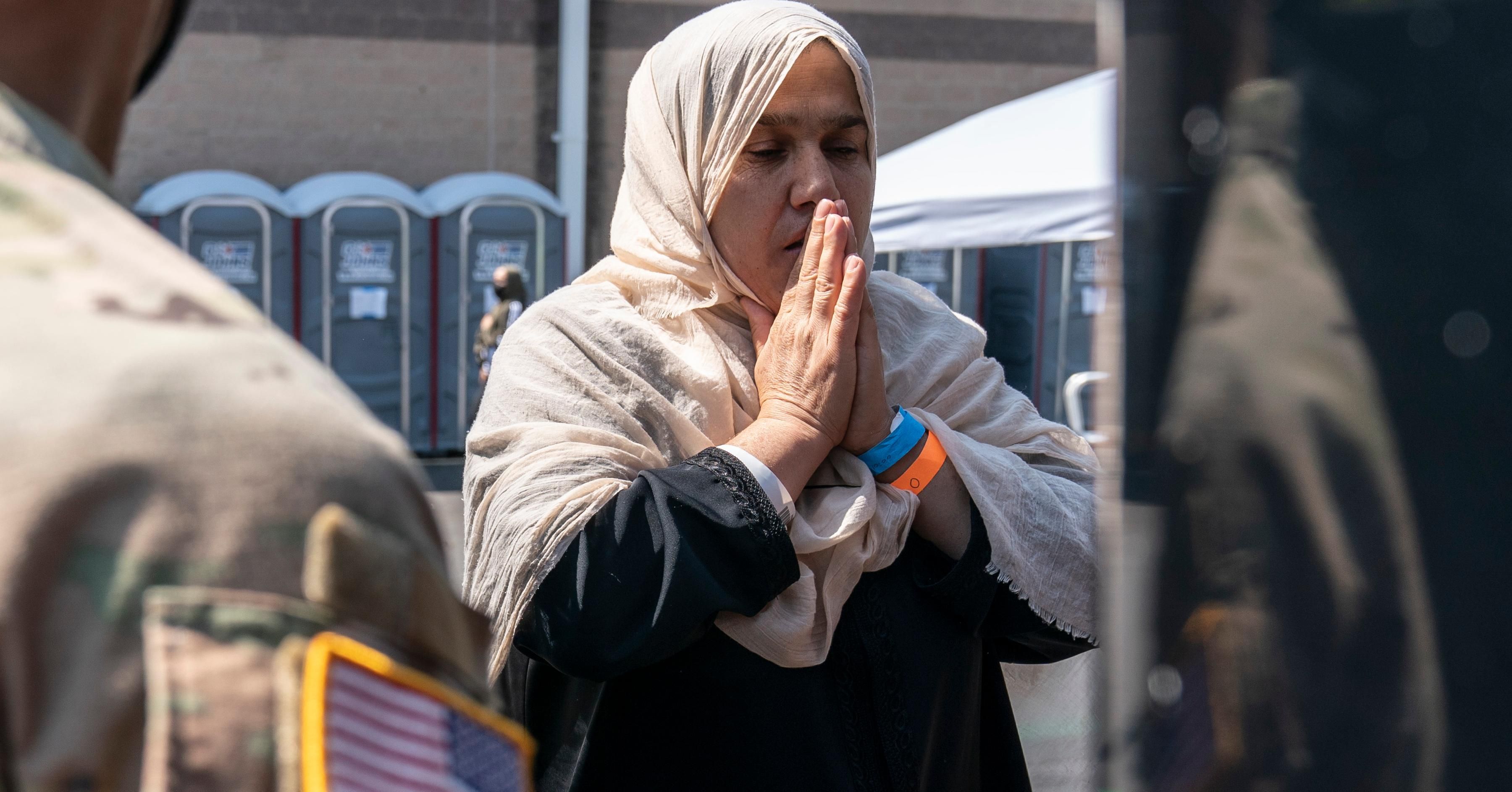 A woman prays as she boards a bus at a processing center for refugees evacuated from Afghanistan at the Dulles Expo Center on August 24, 2021 in Chantilly, Virginia.on August 24, 2021 in Chantilly, Virginia. According to the U.S. State Department, between Sunday morning and Monday morning, 10,400 people were evacuated from Kabul on military flights and approximately 5,900 more people were evacuated on 61 coalition aircraft.(Photo by Joshua Roberts/Getty Images)