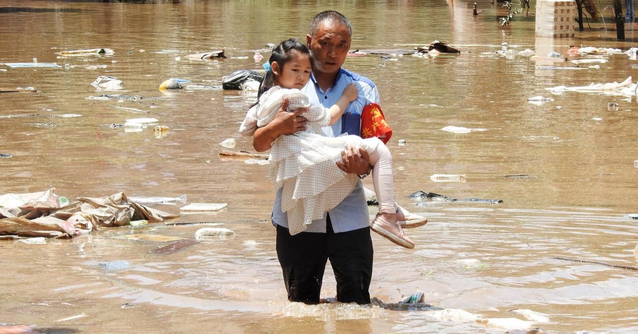 A girl is carried to safety after flooding in southern China