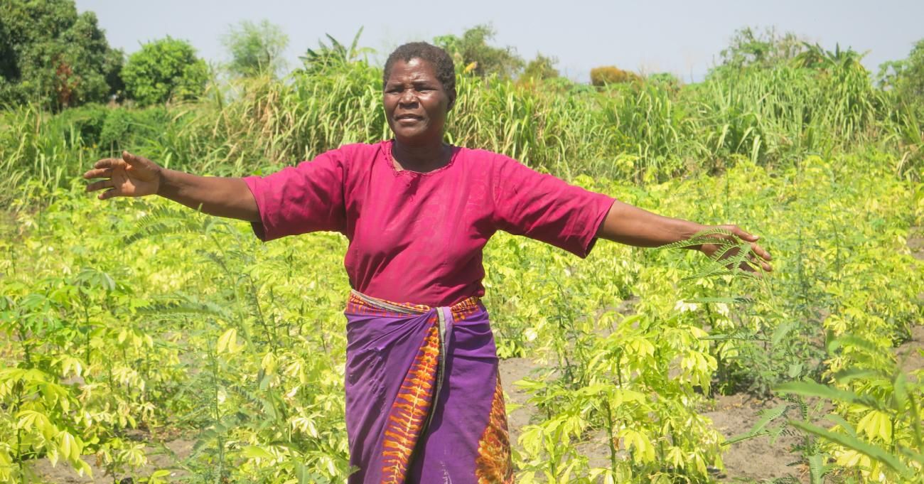 A woman in Malawi gestures to crops