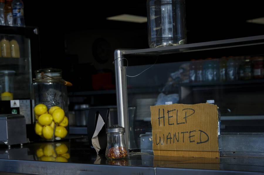 A "help wanted" sign is seen at a restaurant