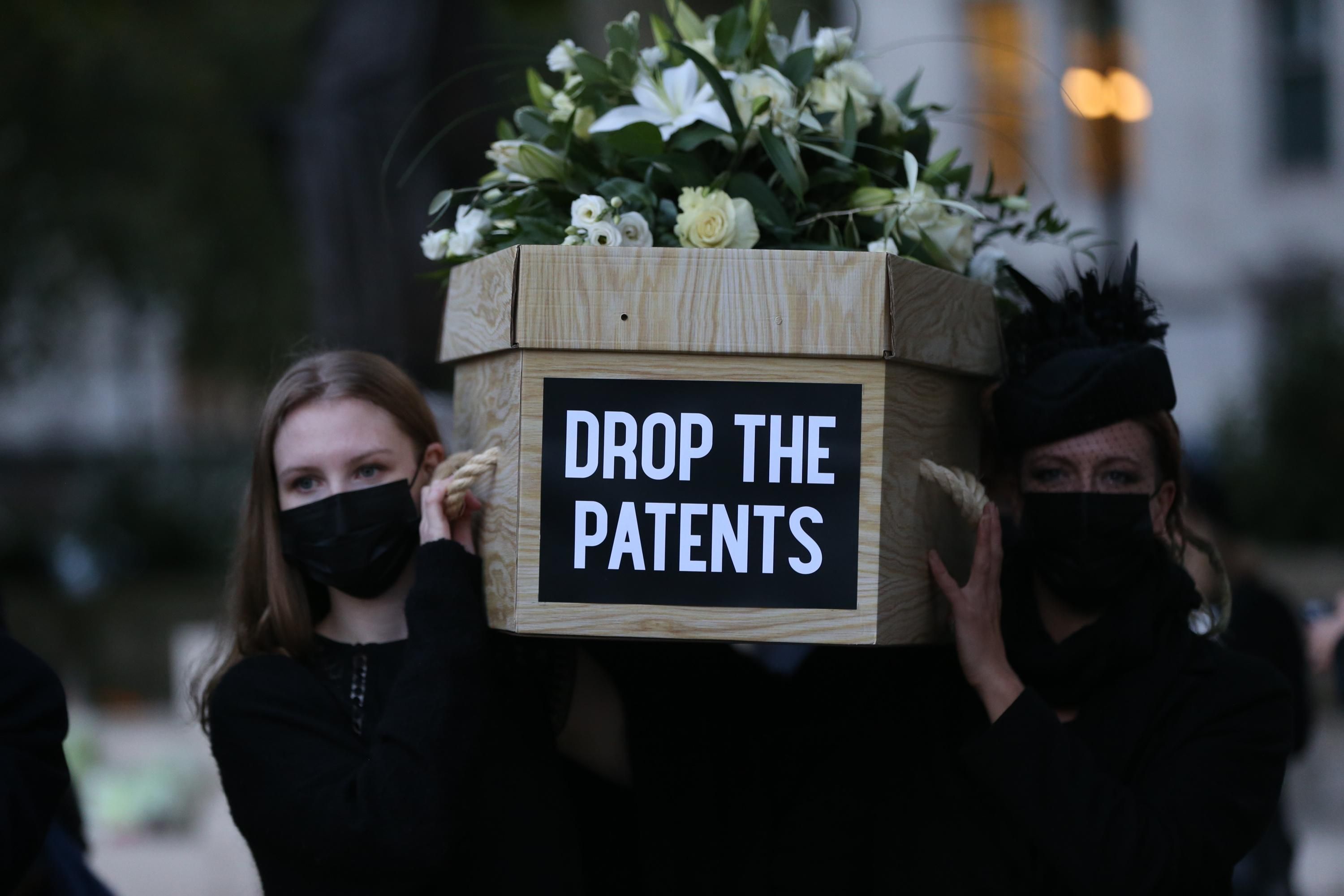 Vaccine equity campaigners carry a mock coffin in London.