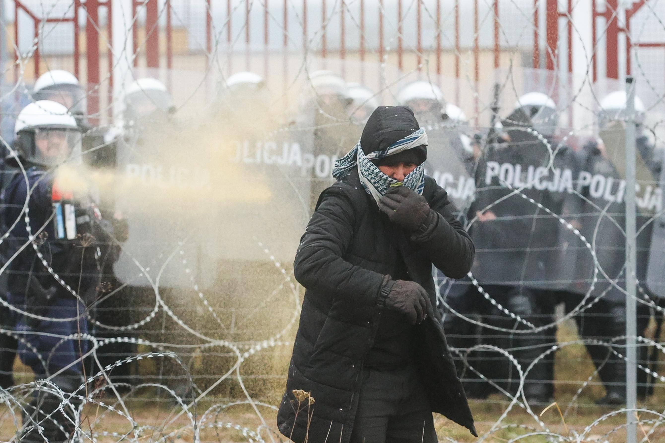 Polish riot police officers and a migrant are seen near the Bruzgi-Kuznica crossing point on the Belarusian-Polish border.