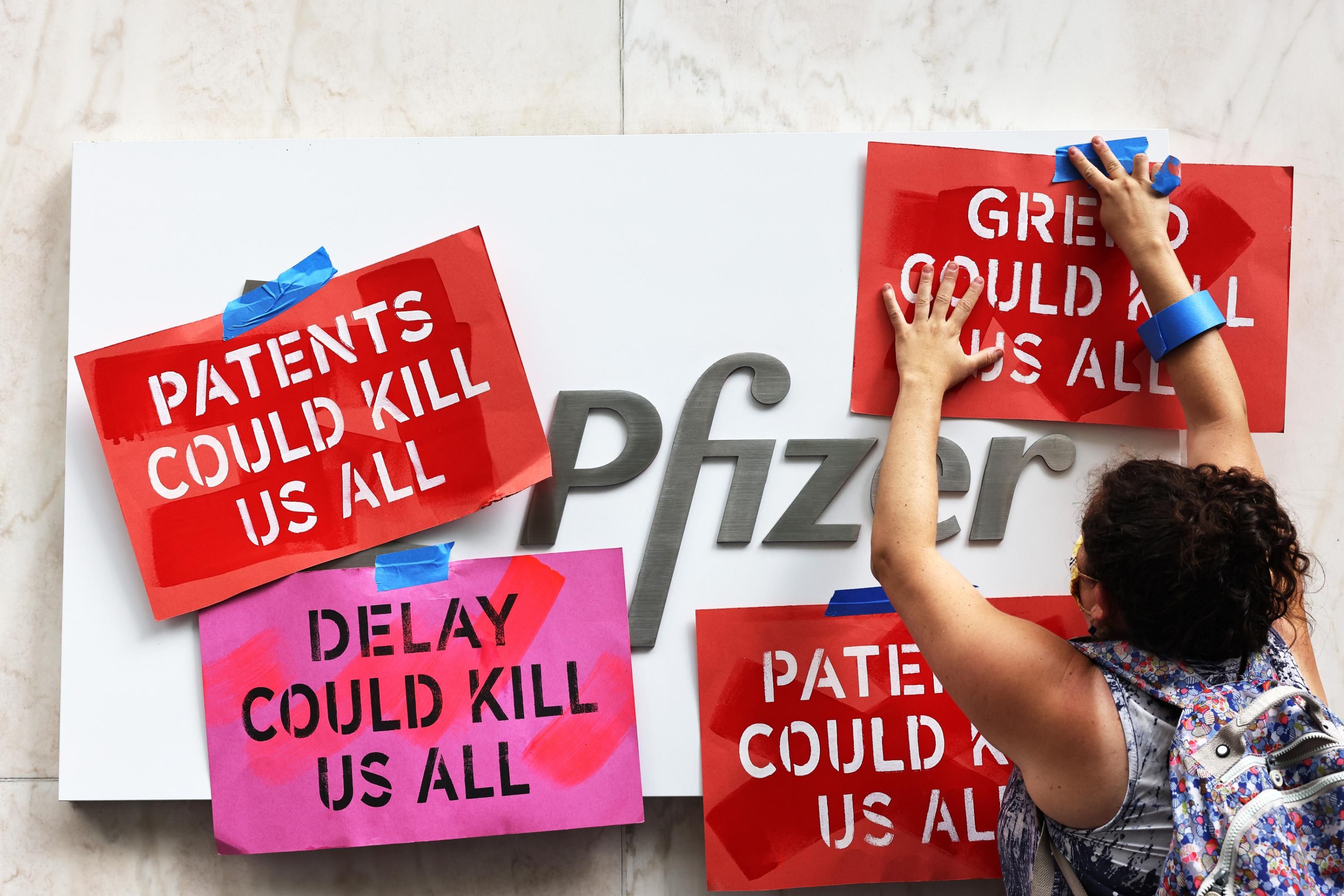 A demonstrator attaches signs to the Pfizer logo