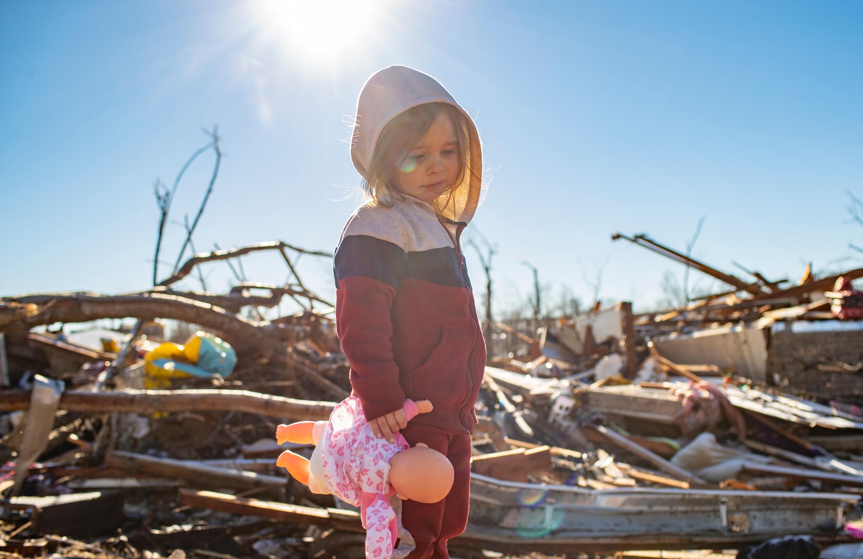A child stands amid the rubble left by a devastating tornado system.