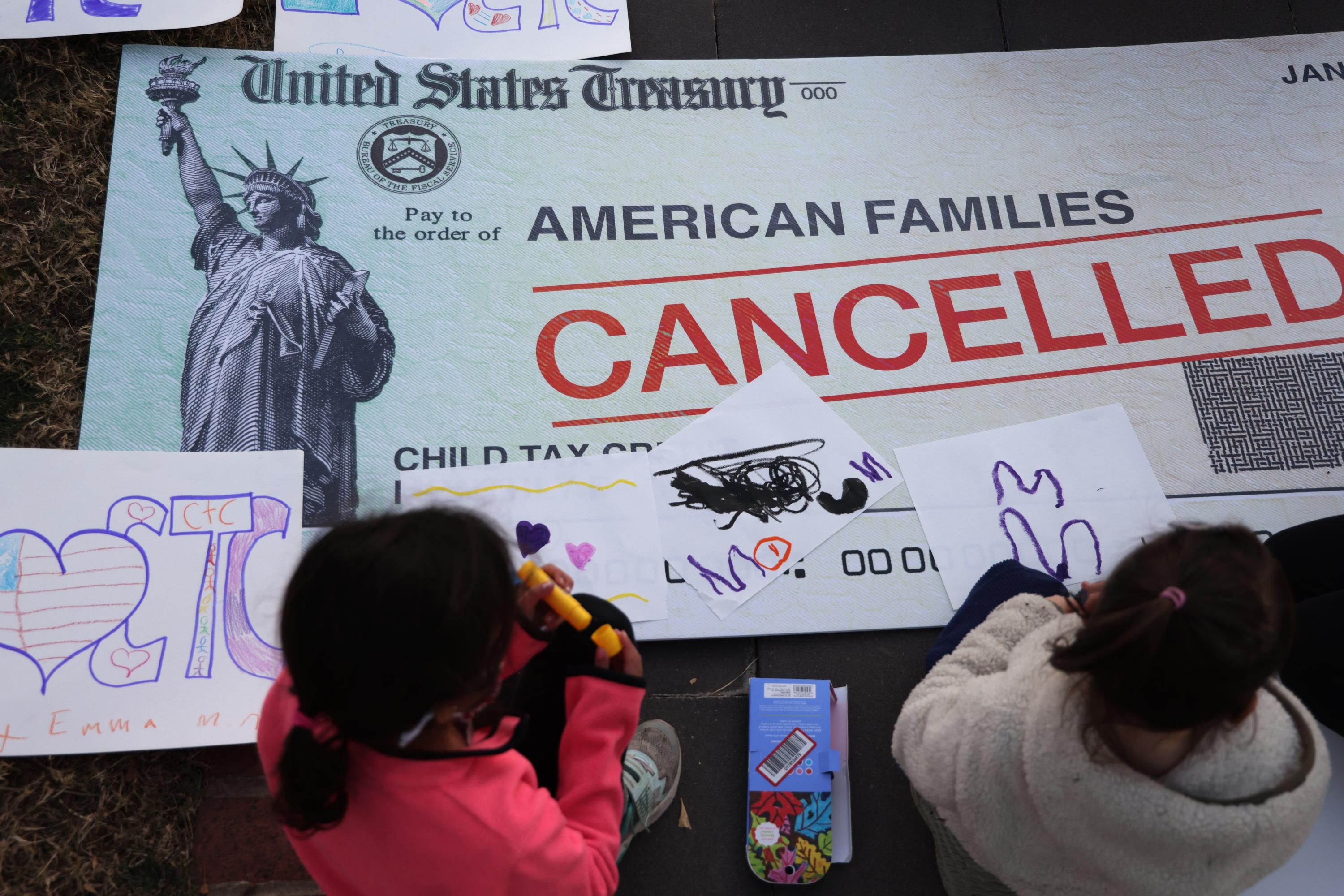 Children draw on a "cancelled check" prop at a rally for the child tax credit