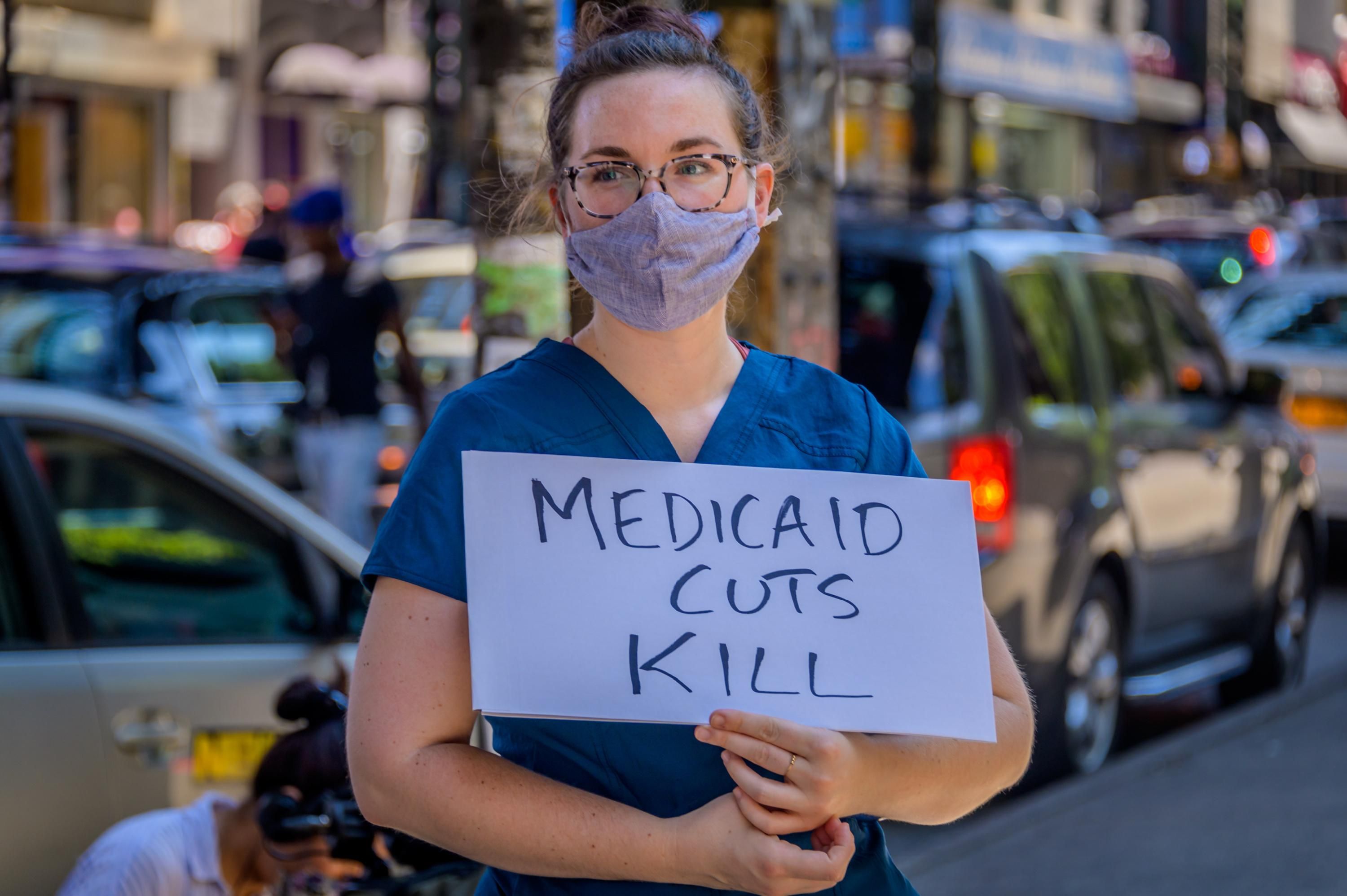 A demonstrator holds a "Medicaid Cuts Kill" sign at a rally